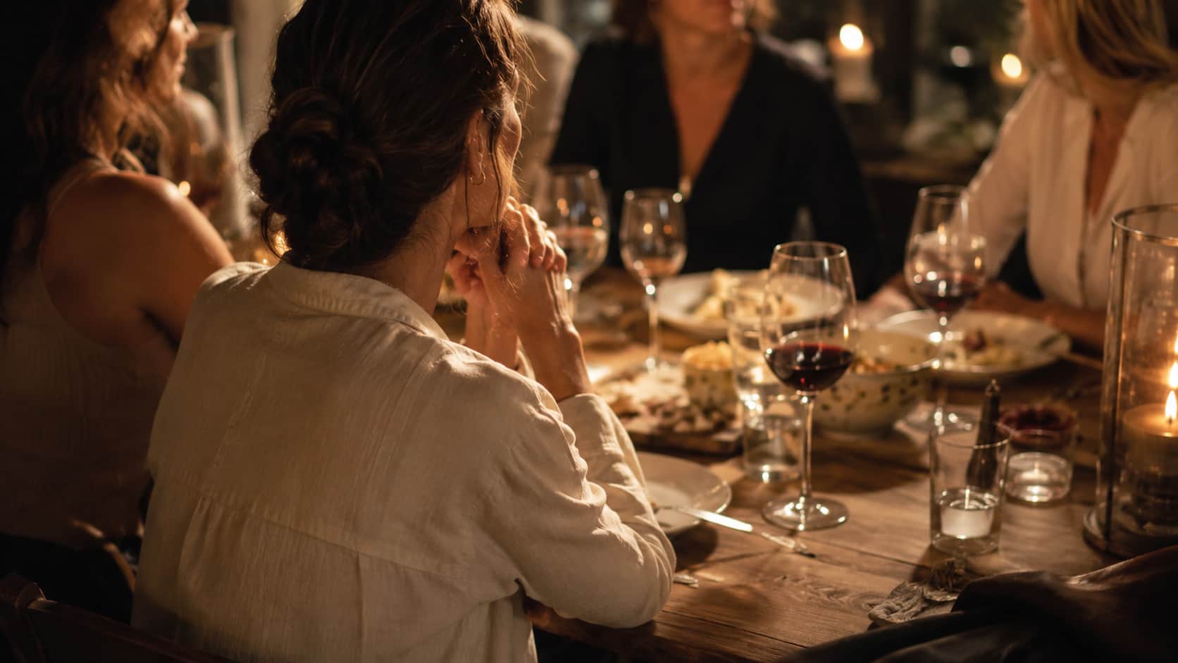 Mulher em mesa de jantar entre outras pessoas